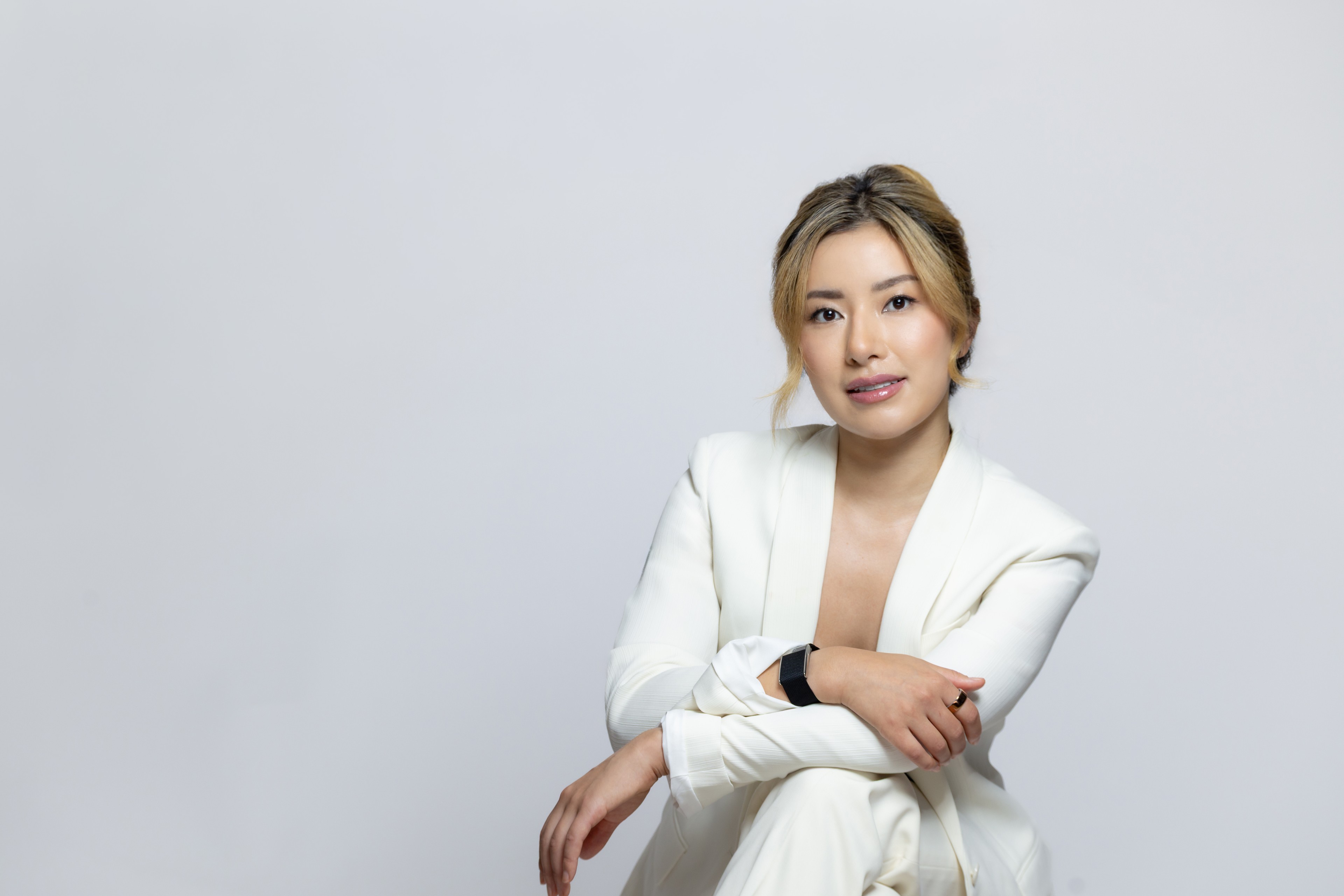 Elaine He posing confidently in a white blazer against a white background